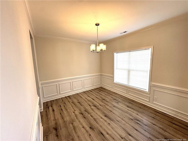 spare room featuring ornamental molding, wood finished floors, visible vents, and a notable chandelier