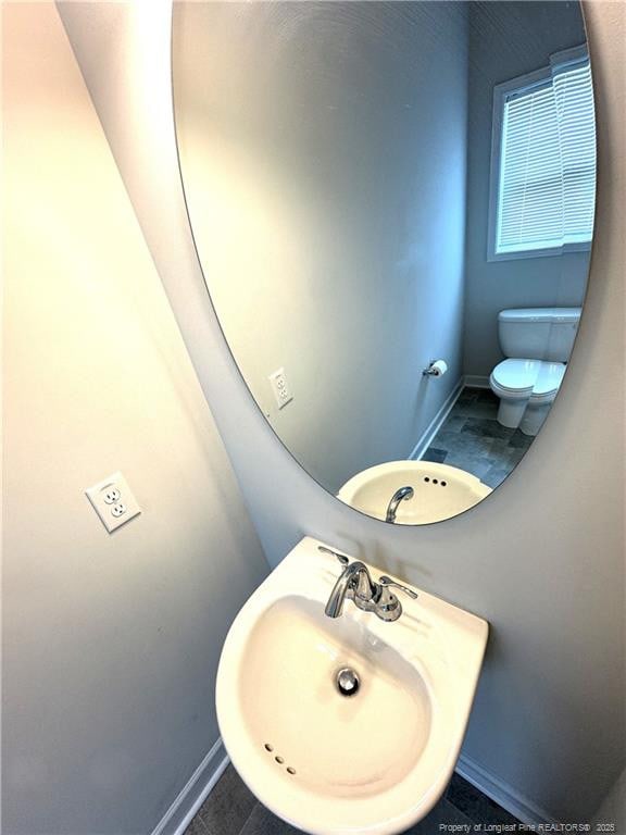 bathroom with baseboards, a sink, and toilet