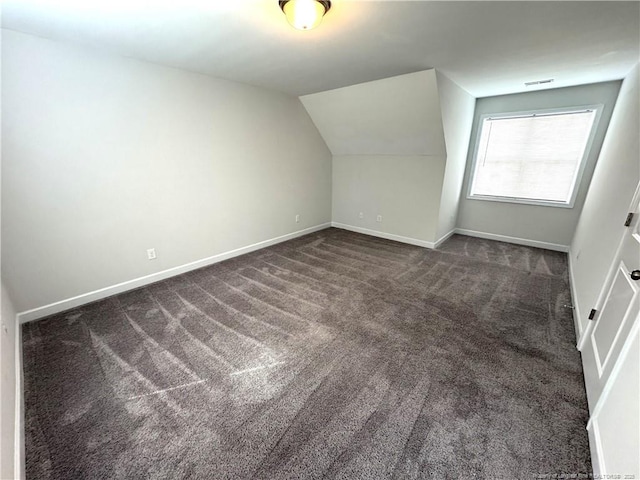 bonus room featuring lofted ceiling, dark carpet, and baseboards