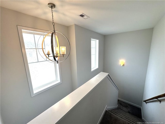 staircase featuring baseboards, carpet floors, visible vents, and an inviting chandelier