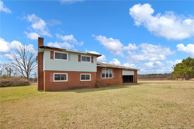 rear view of property with a chimney, a lawn, and brick siding