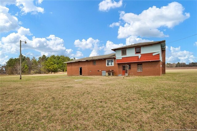 back of property with brick siding and a yard