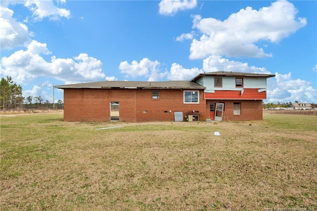 back of property featuring a yard and brick siding