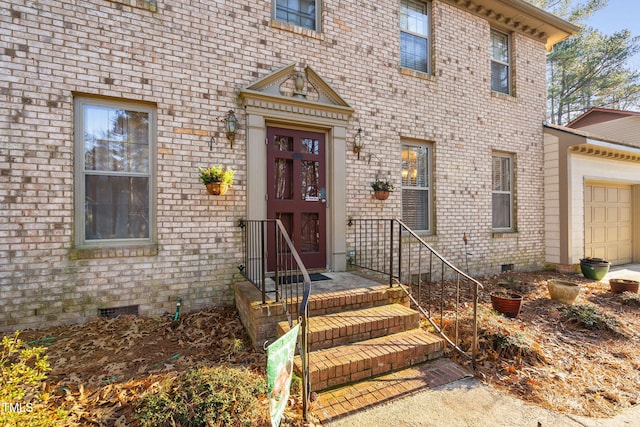 view of exterior entry with crawl space, brick siding, and an attached garage