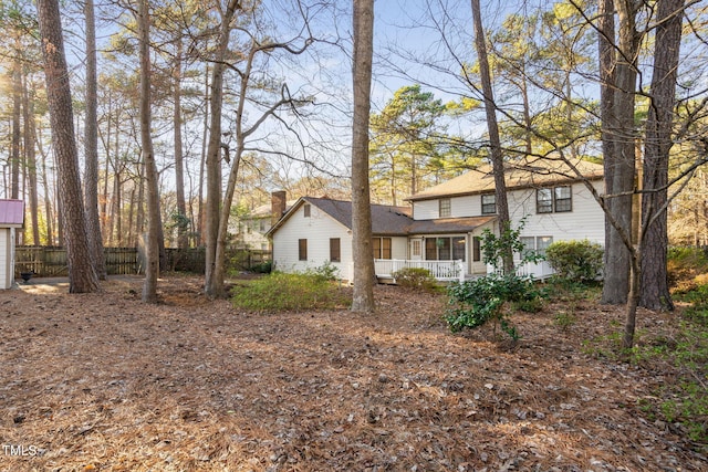 exterior space with a porch, fence, and a chimney