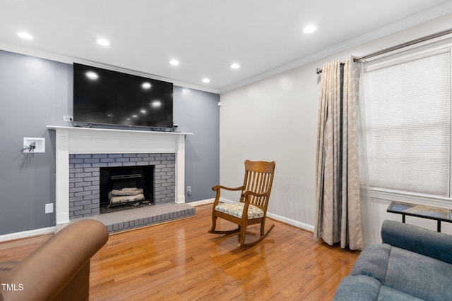 living area with a fireplace, crown molding, baseboards, and wood finished floors