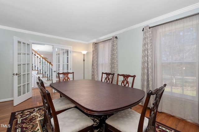 dining area featuring stairway, ornamental molding, wood finished floors, and french doors