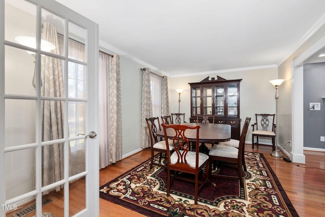 dining area featuring french doors, ornamental molding, wood finished floors, and baseboards