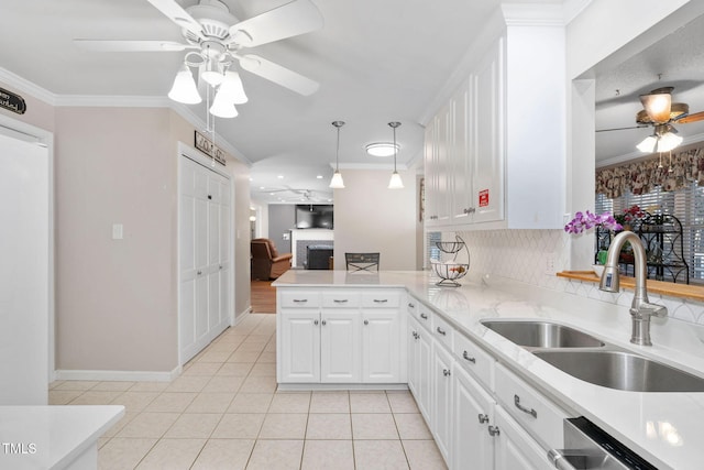 kitchen with light tile patterned floors, a peninsula, a sink, crown molding, and stainless steel dishwasher