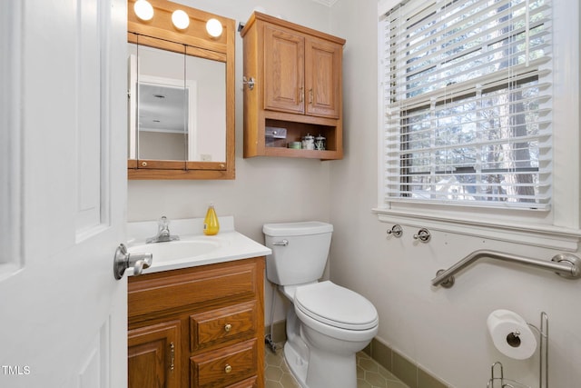half bath featuring baseboards, vanity, toilet, and a healthy amount of sunlight