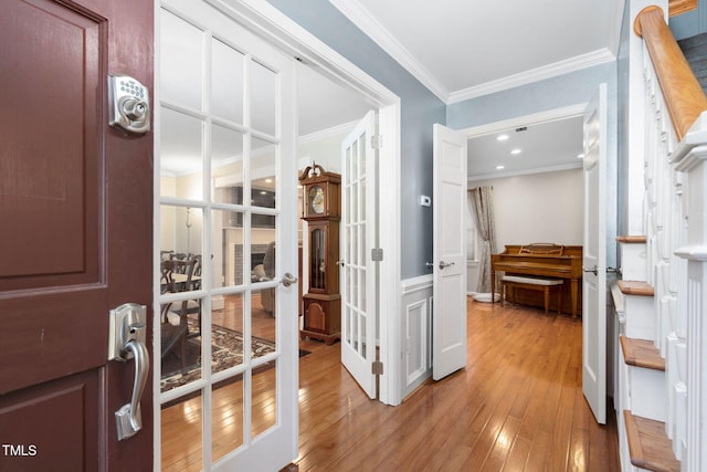 interior space featuring light wood-style floors, french doors, and crown molding