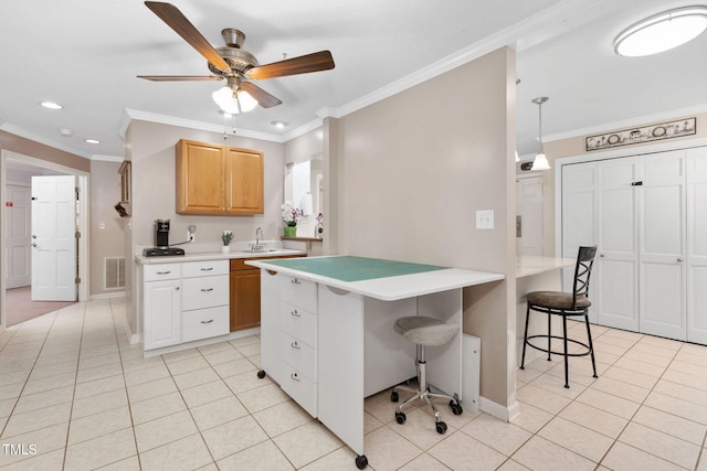 kitchen with light countertops, ornamental molding, a breakfast bar area, and light tile patterned flooring