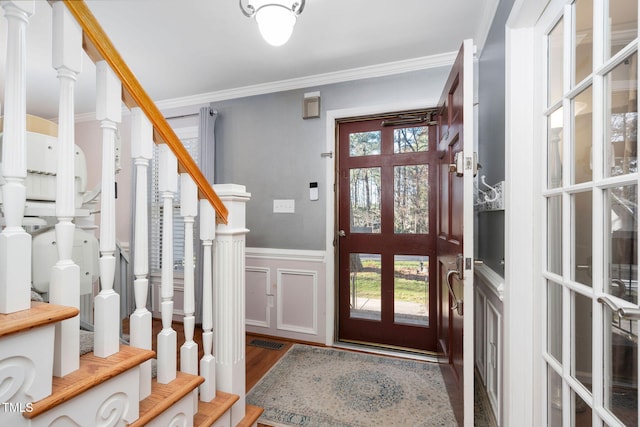 entryway with ornamental molding, stairway, wainscoting, and wood finished floors