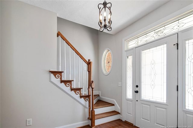 4305 Sanderosa Rd, Fayetteville, NC 28312 - foyer with baseboards, dark wood-style flooring, an inviting chandelier, stairs, and a textured ceiling