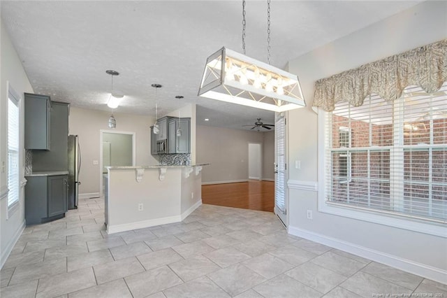 4305 Sanderosa Rd, Fayetteville, NC 28312 - kitchen featuring a breakfast bar area, a ceiling fan, appliances with stainless steel finishes, gray cabinets, and backsplash