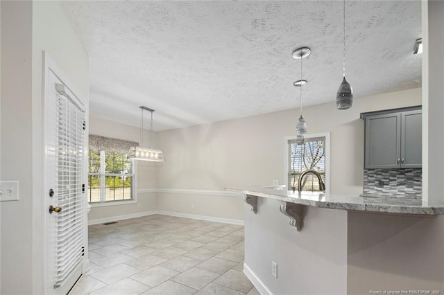 4305 Sanderosa Rd, Fayetteville, NC 28312 - kitchen with light stone countertops, a textured ceiling, gray cabinetry, pendant lighting, and a sink