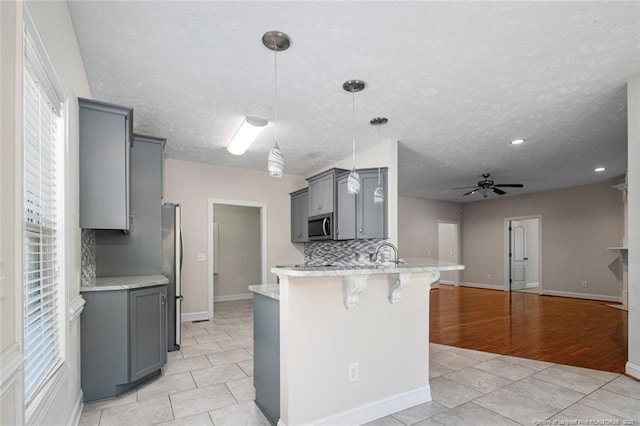 4305 Sanderosa Rd, Fayetteville, NC 28312 - kitchen featuring appliances with stainless steel finishes, a breakfast bar, a peninsula, gray cabinets, and backsplash