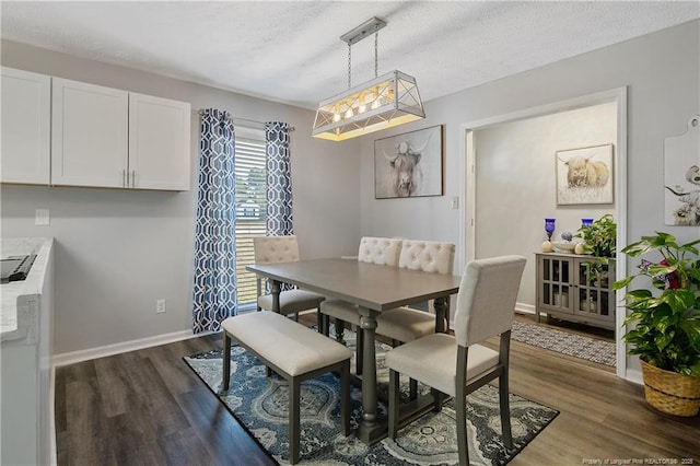 dining space with dark wood-style flooring, a textured ceiling, and baseboards