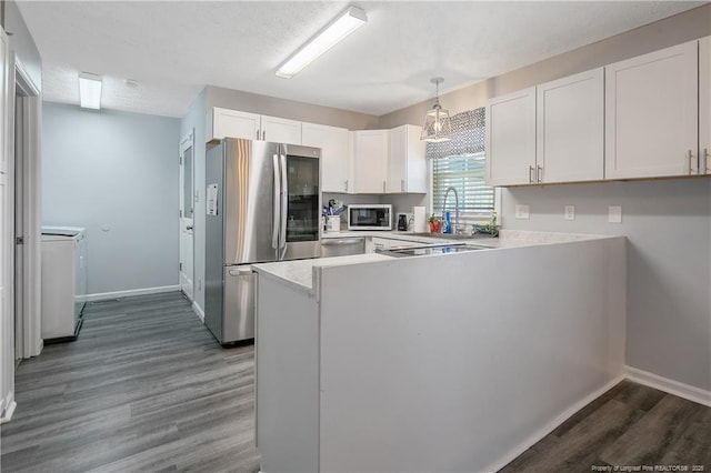 kitchen with dark wood-style floors, light countertops, appliances with stainless steel finishes, white cabinetry, and a peninsula