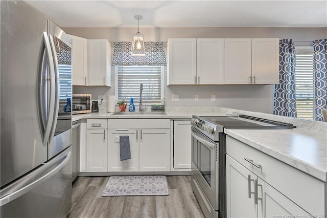 kitchen featuring a sink, white cabinets, light countertops, appliances with stainless steel finishes, and light wood-type flooring