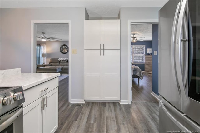 kitchen featuring dark wood-style flooring, light countertops, appliances with stainless steel finishes, white cabinets, and a textured ceiling