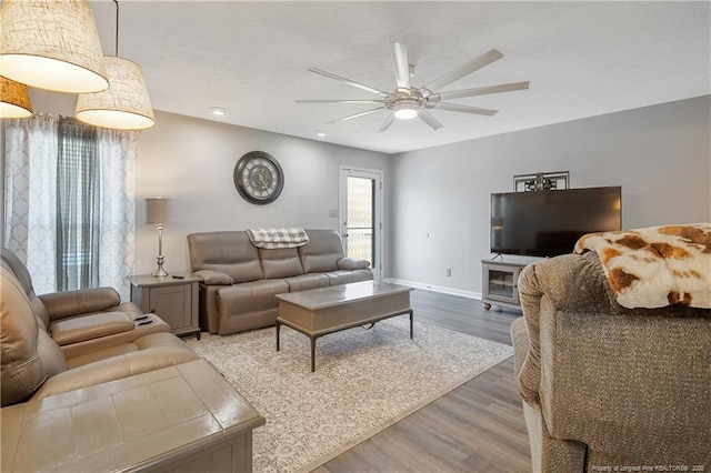 living room featuring ceiling fan, baseboards, and wood finished floors