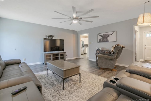 living room with wood finished floors, a ceiling fan, and baseboards