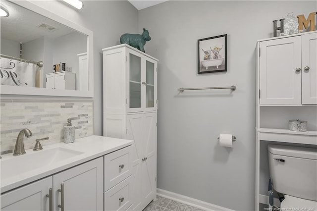 bathroom with visible vents, toilet, decorative backsplash, vanity, and baseboards