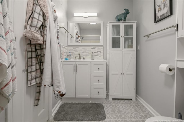 bathroom with baseboards, tile patterned floors, vanity, and decorative backsplash