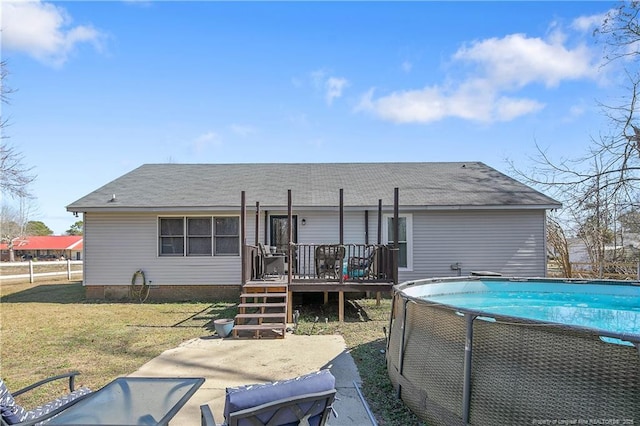 rear view of property with an outdoor pool, a lawn, and a deck