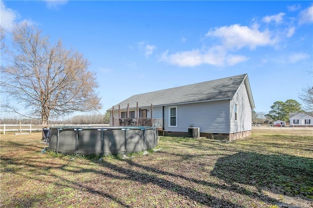 back of house with an outdoor pool, crawl space, central AC, and a lawn