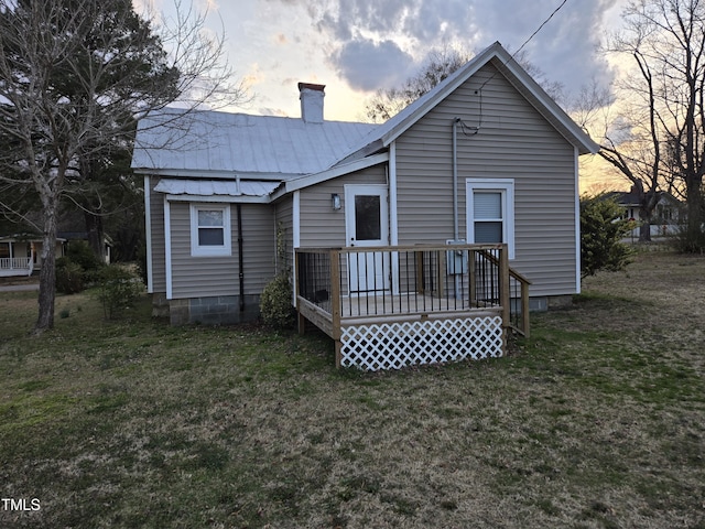 rear view of property with a yard, metal roof, a chimney, and a wooden deck