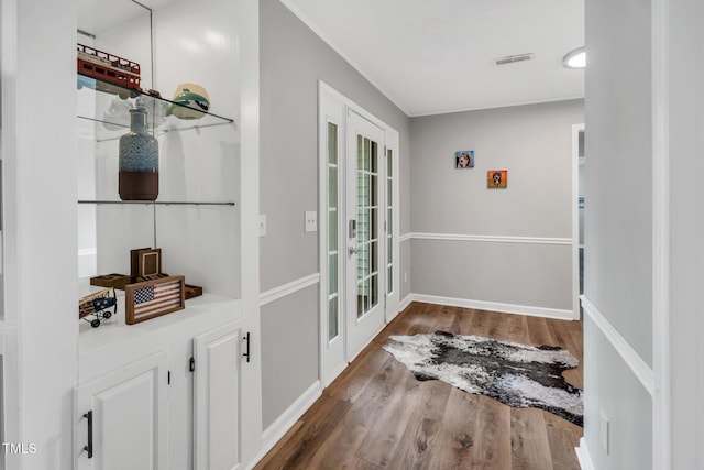 doorway with french doors, wood finished floors, visible vents, and baseboards