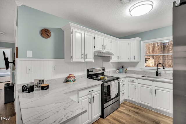 kitchen with light wood-style floors, white cabinets, a sink, under cabinet range hood, and stainless steel electric range