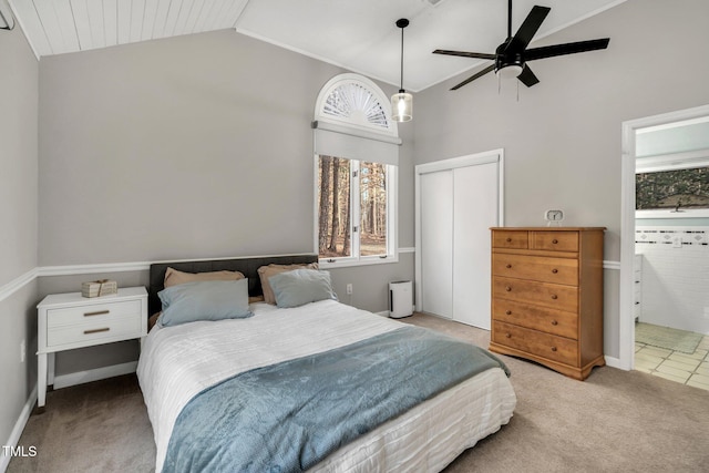 carpeted bedroom with lofted ceiling, a closet, and ensuite bath