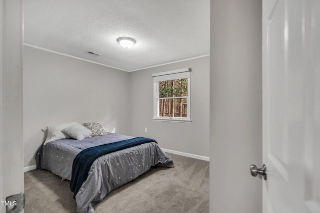 carpeted bedroom featuring a textured ceiling, ornamental molding, visible vents, and baseboards