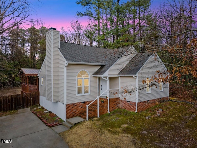 view of front of property featuring crawl space, a shingled roof, a chimney, and fence