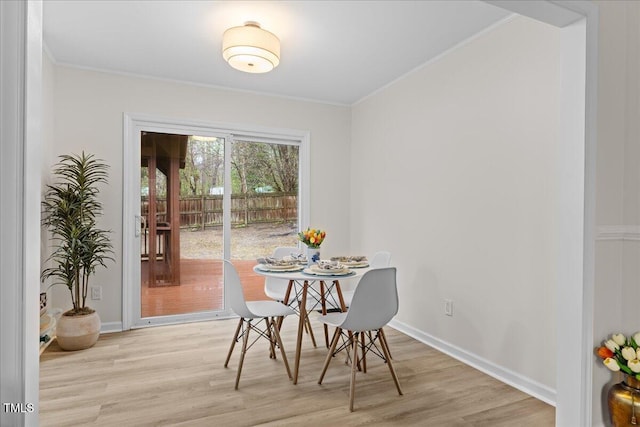 dining room featuring ornamental molding, light wood-type flooring, and baseboards