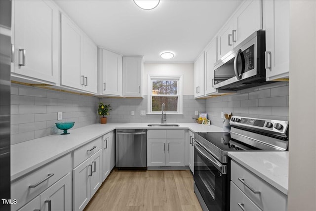 kitchen with decorative backsplash, stainless steel appliances, light countertops, light wood-style floors, and a sink