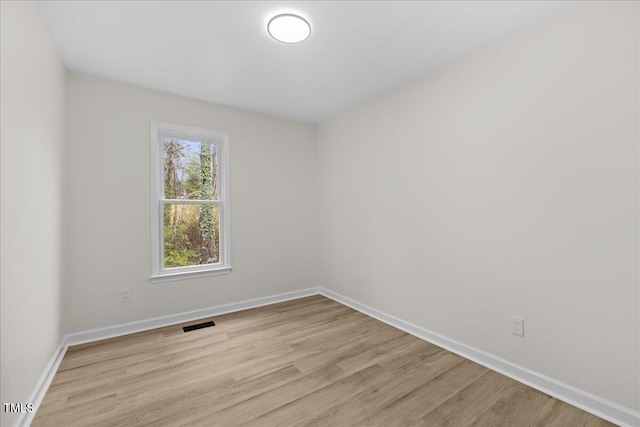 empty room featuring light wood finished floors, visible vents, and baseboards