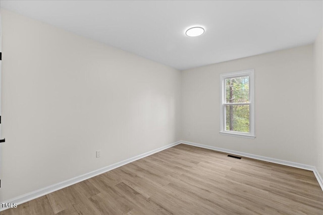 spare room with baseboards, visible vents, and light wood finished floors