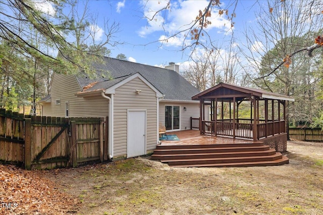 back of house with a shingled roof, a chimney, a gate, fence, and a wooden deck