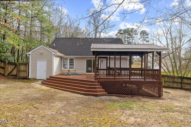 rear view of property with metal roof, a chimney, fence, and a wooden deck