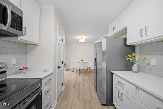 kitchen with light wood finished floors, light countertops, appliances with stainless steel finishes, and white cabinetry