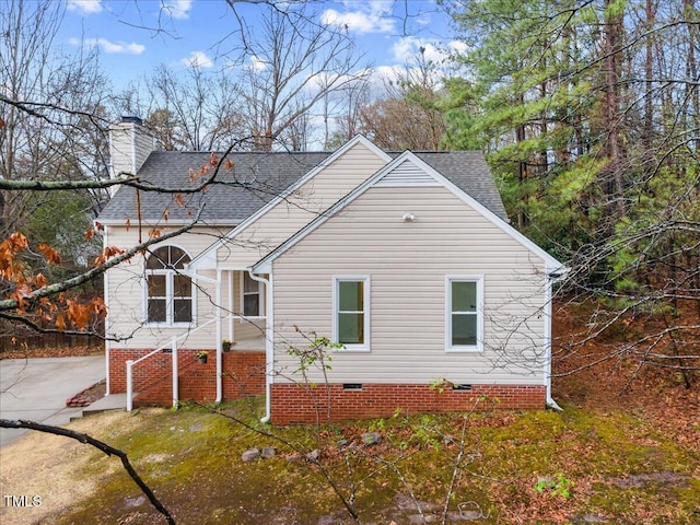 view of front of house featuring crawl space, a shingled roof, and a chimney