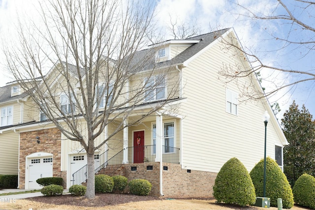 view of front of property featuring an attached garage, stone siding, a shingled roof, and covered porch