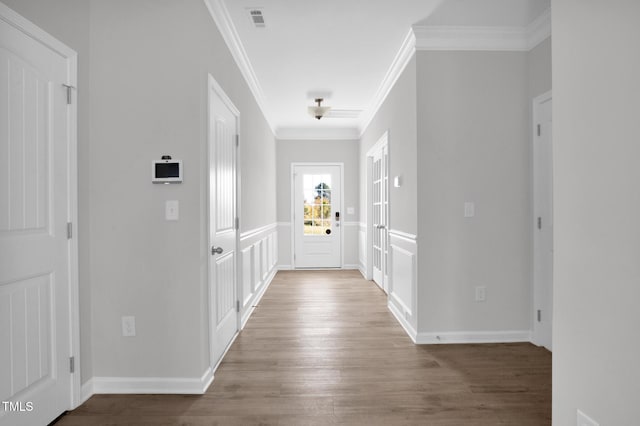 entrance foyer with ornamental molding, wood finished floors, visible vents, and baseboards