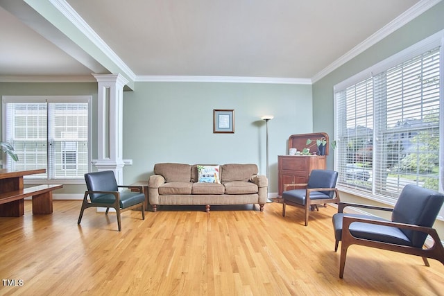 living area featuring ornamental molding, baseboards, decorative columns, and light wood-style floors