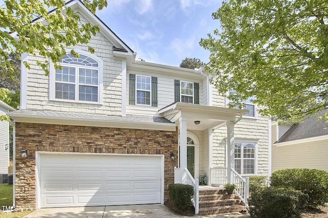 traditional-style home with an attached garage, stone siding, and driveway