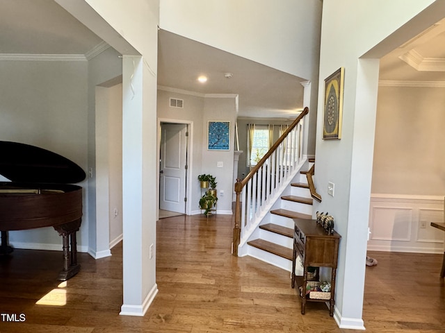 entrance foyer with crown molding, wood finished floors, visible vents, stairway, and ornate columns